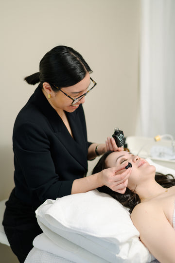 Woman receiving a facial treatment from another woman in a professional setting.