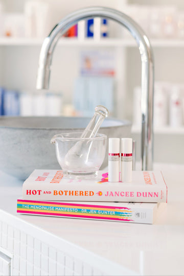 Books and a mortar and pestle on a kitchen counter with a sink in the background