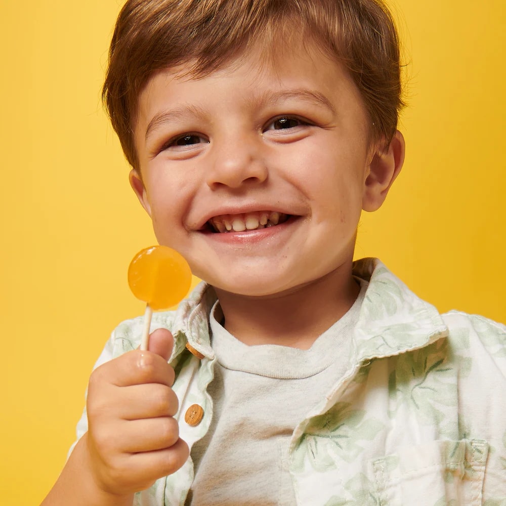 Child holding a lollipop against a yellow background