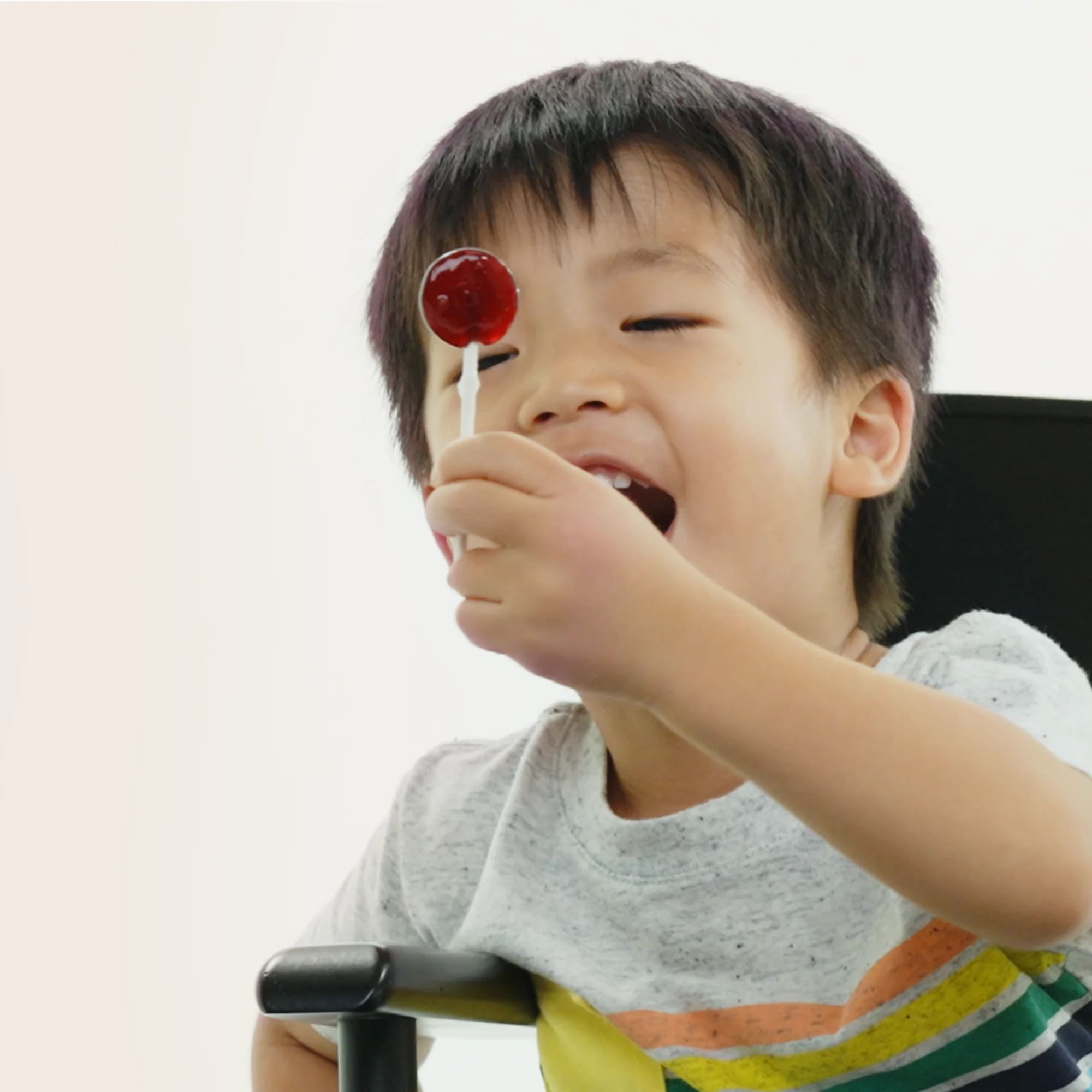 Child eating a lollipop with a plain background