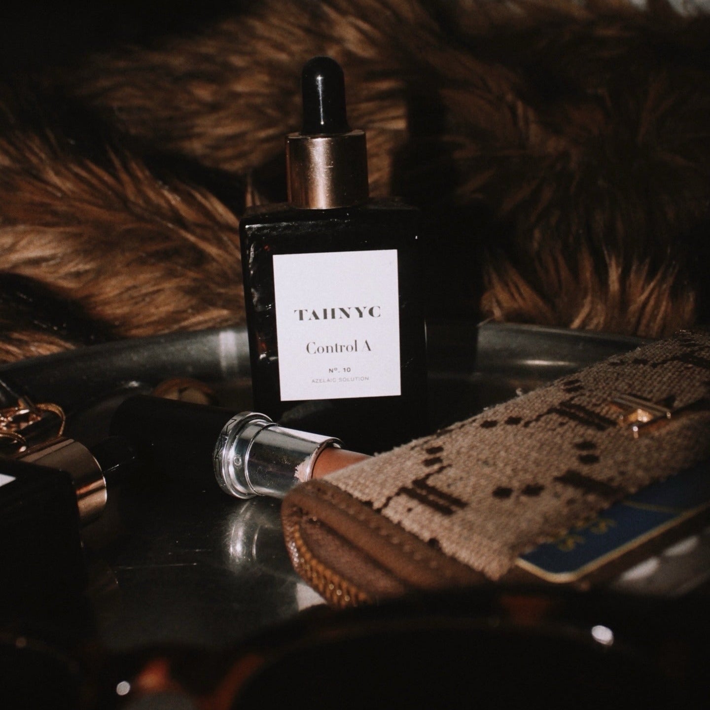 Black perfume bottle with a white label on a reflective surface with a fur background