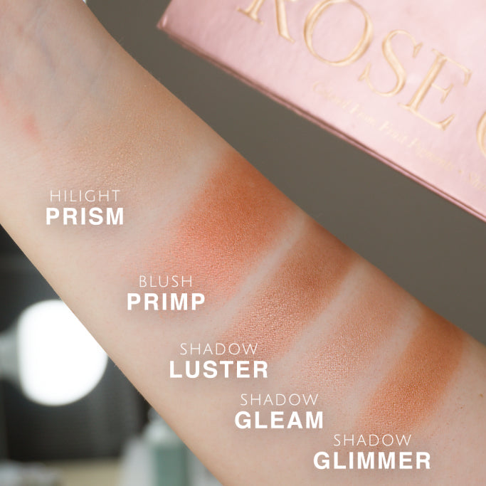 Rose gold makeup swatches on a person's arm with product packaging in the background.