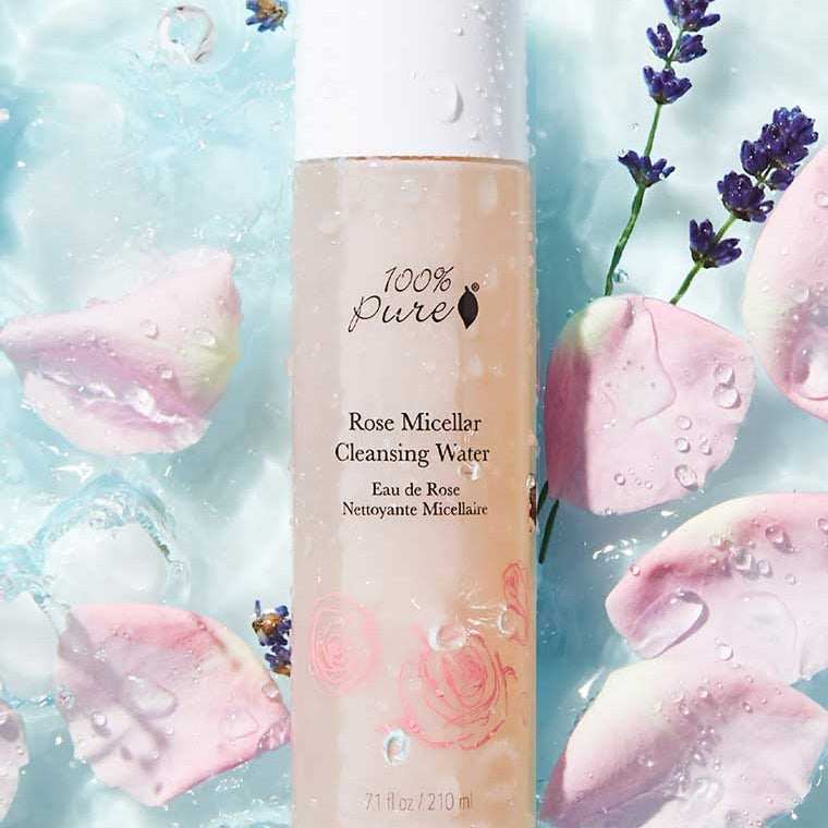 Bottle of 100% Pure Rose Micellar Cleansing Water with floral elements on a light blue background
