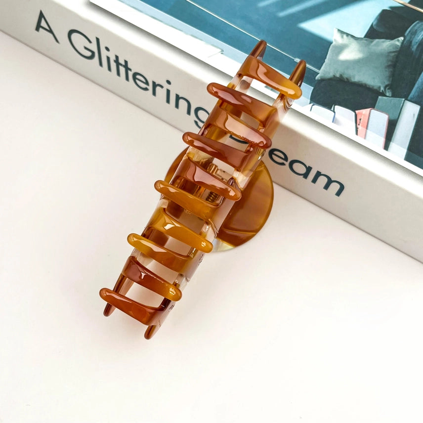Brown hair clip on a white surface with a book in the background