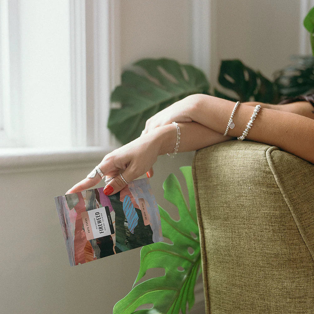 Person holding a magazine with a plant in the foreground