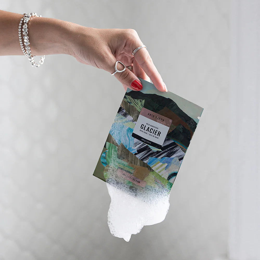 Hand holding a small card with a scenic design against a plain background
