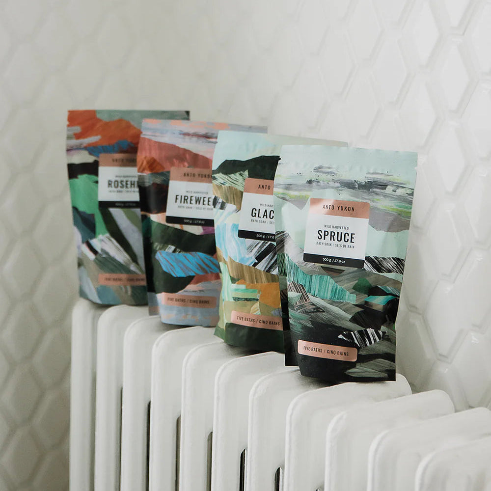 Five coffee bags with different designs and text on a white radiator against a textured white wall.