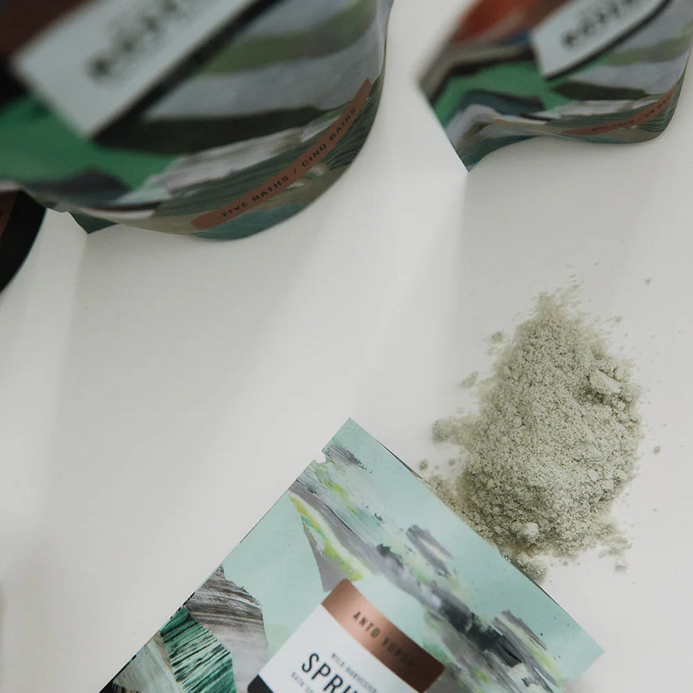 Container of 'Spruce' with a small amount of powder on a white surface