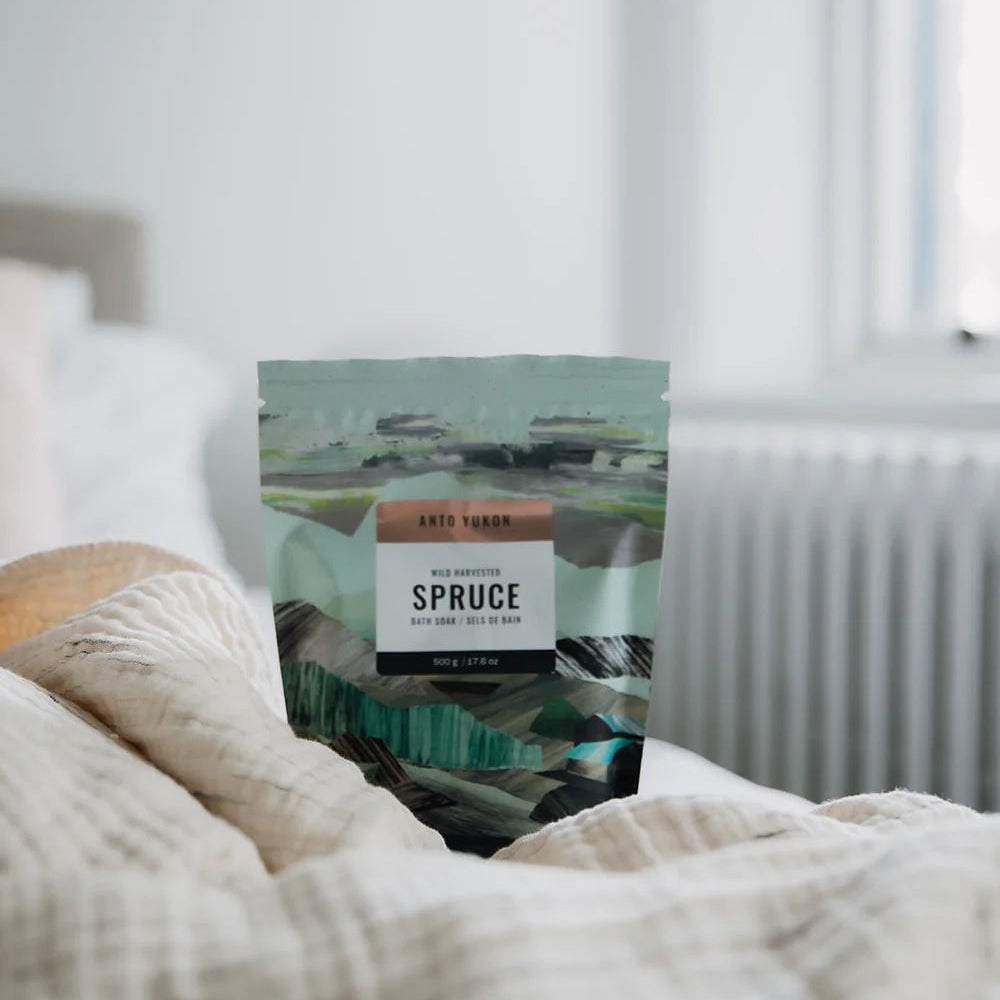 Packaged product labeled 'Spruce' on a bed with a neutral background