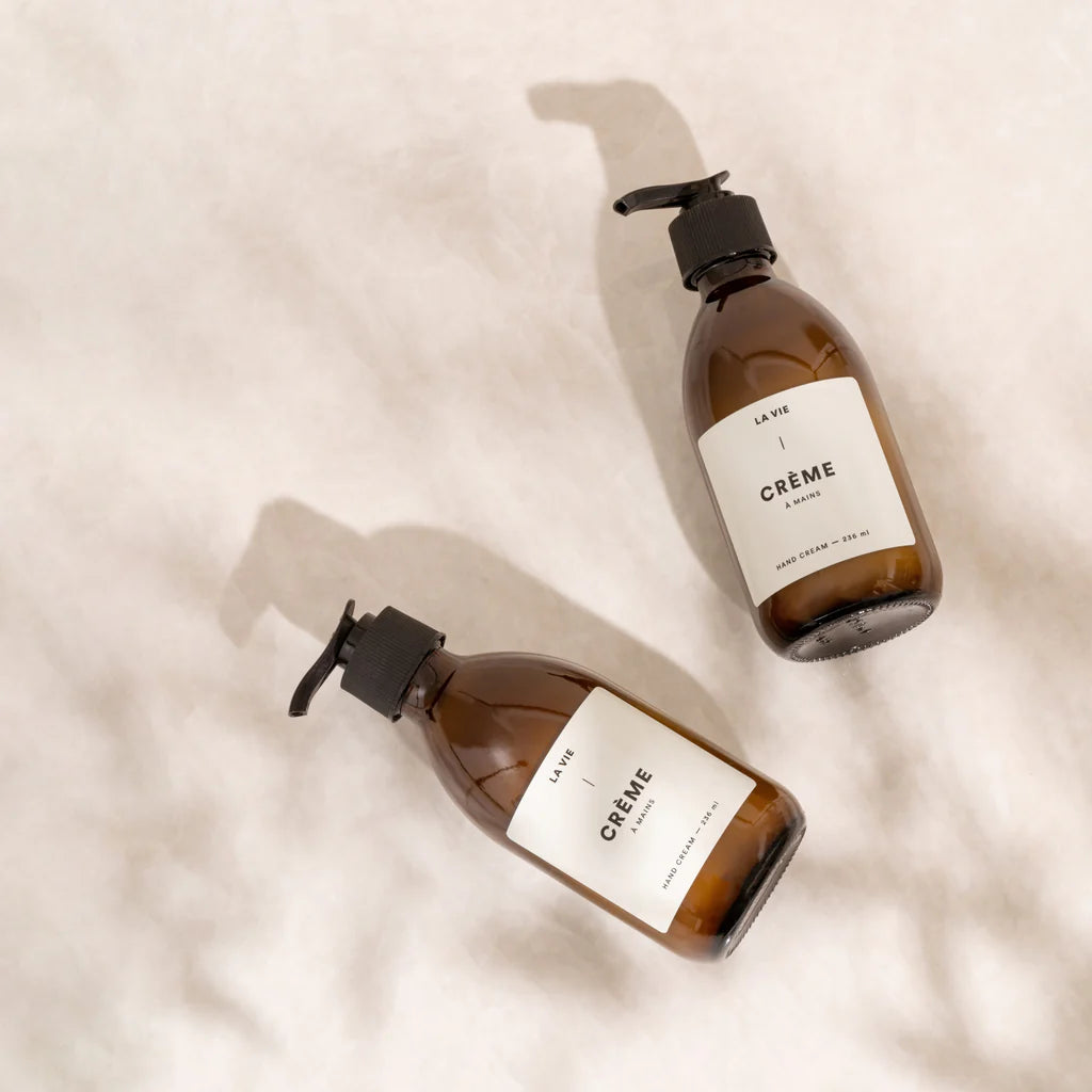 Two brown bottles labeled 'La Vie Crème' on a beige background