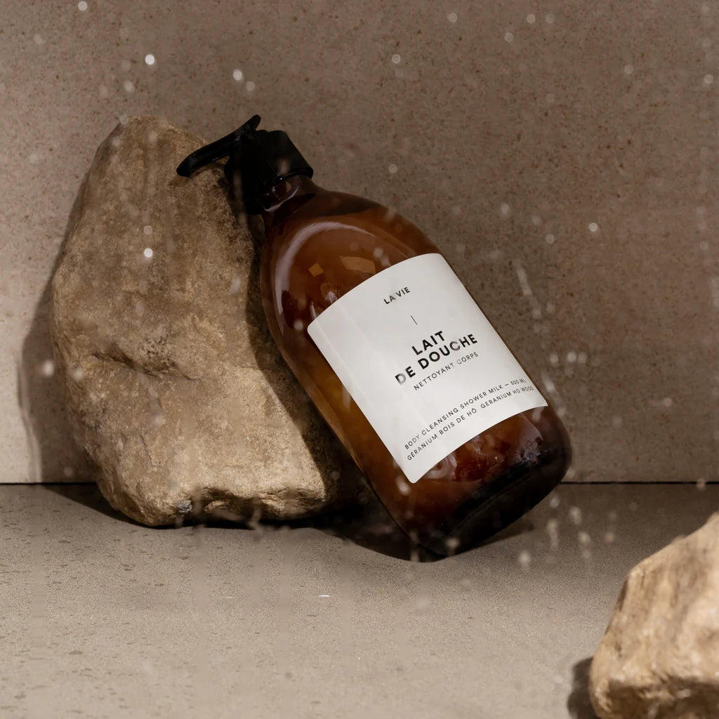 Brown bottle of 'Lait de Douche' with a pump on a white background