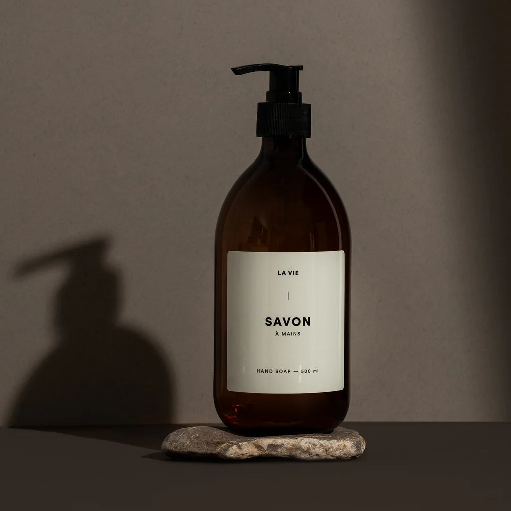 Brown soap bottle with pump on a stone surface against a gray background