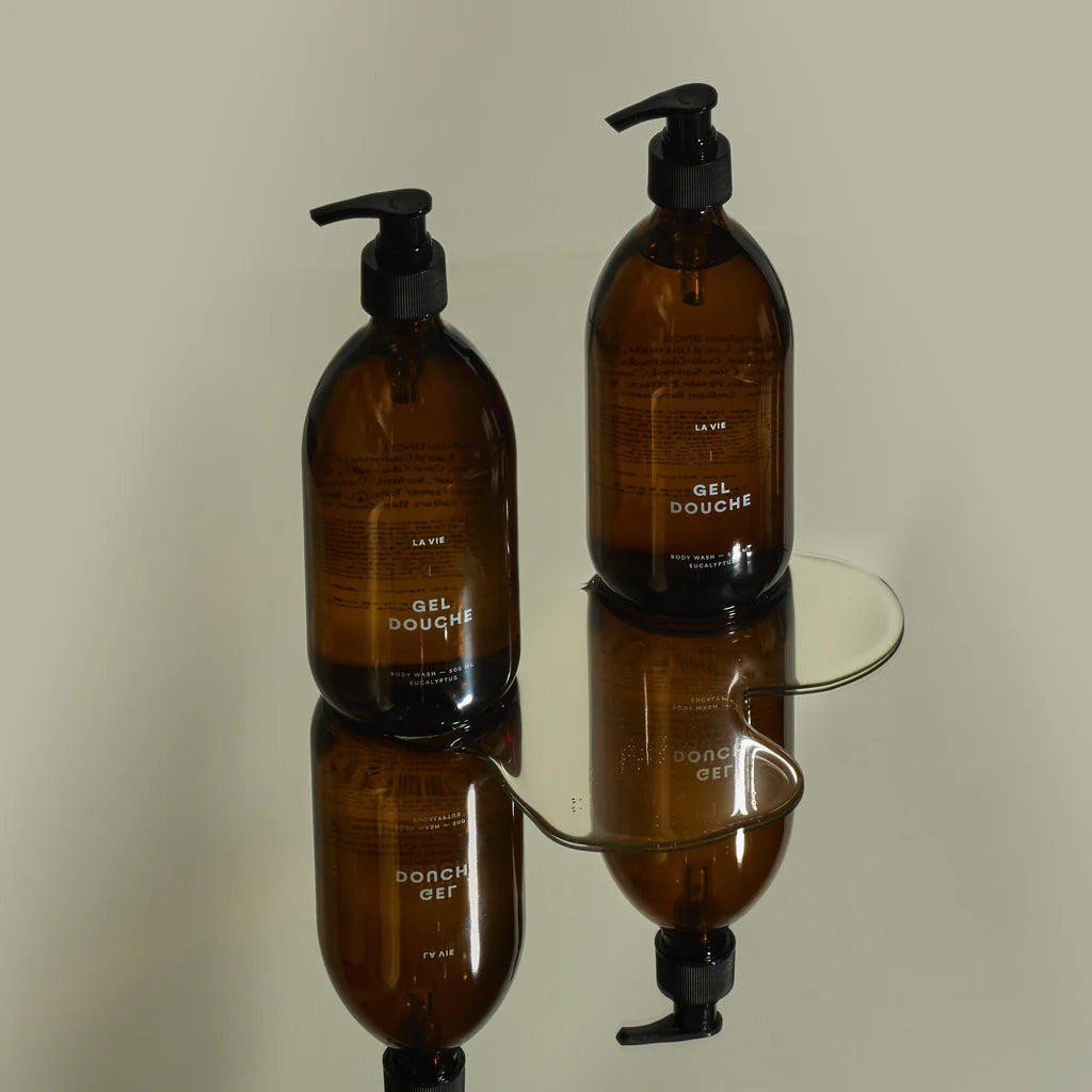 Two brown bottles with black pumps on a reflective surface.