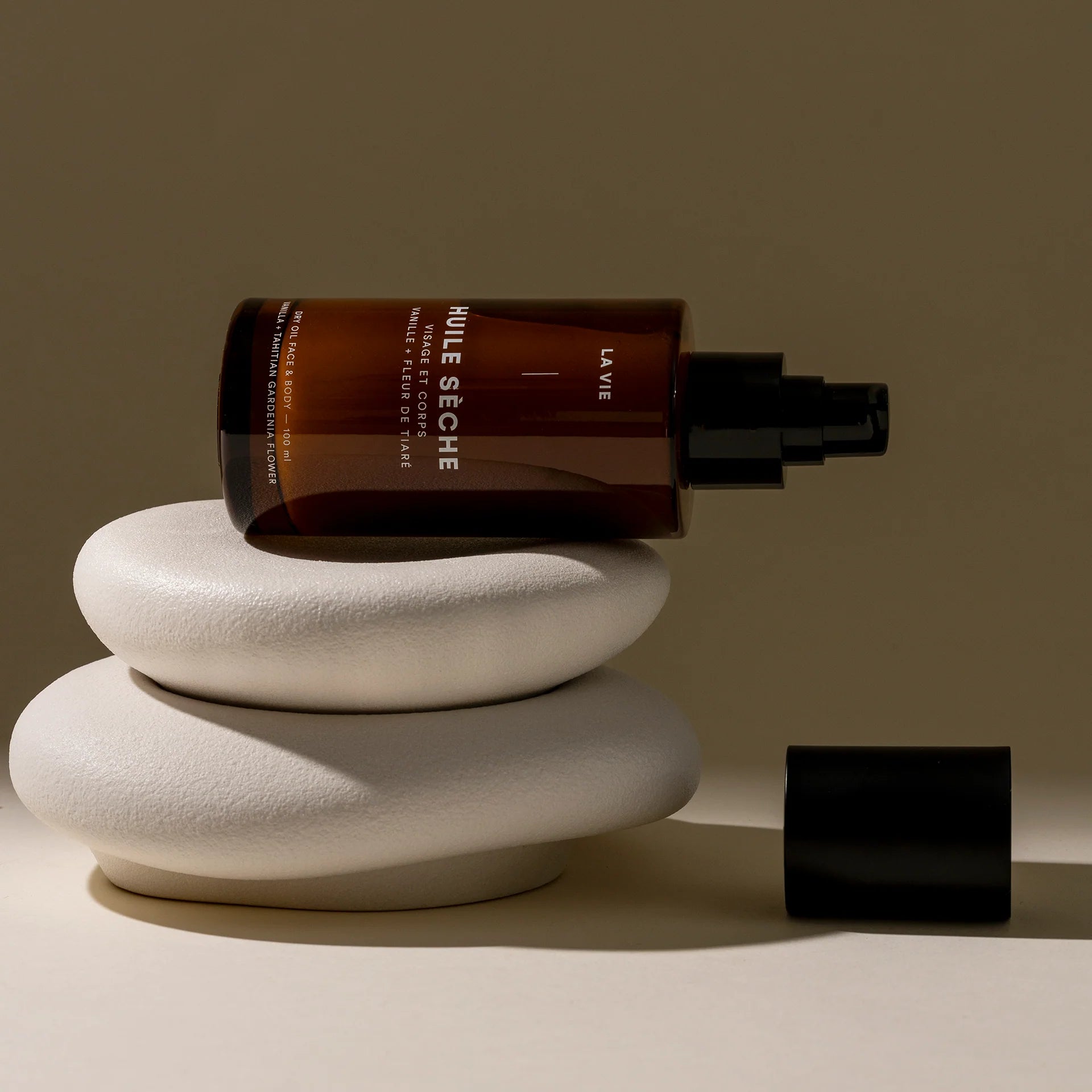 Brown bottle with black cap on a white stone surface against a beige background