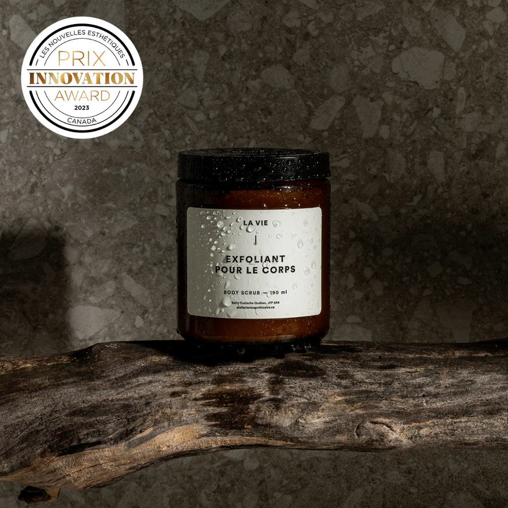 Jar of body scrub with a label on a textured surface, featuring an innovation award badge.
