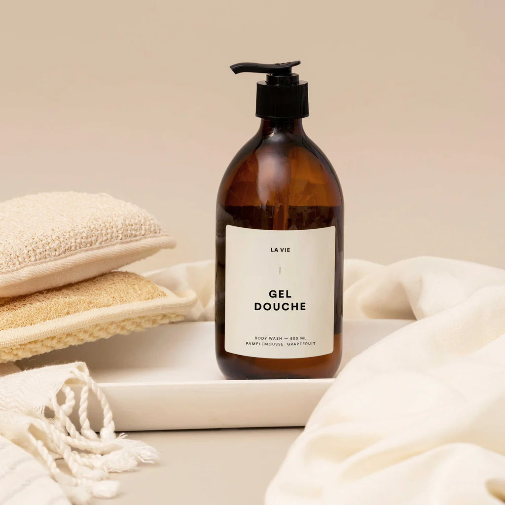 Brown bottle of 'Gel Douche' with a white label on a beige background