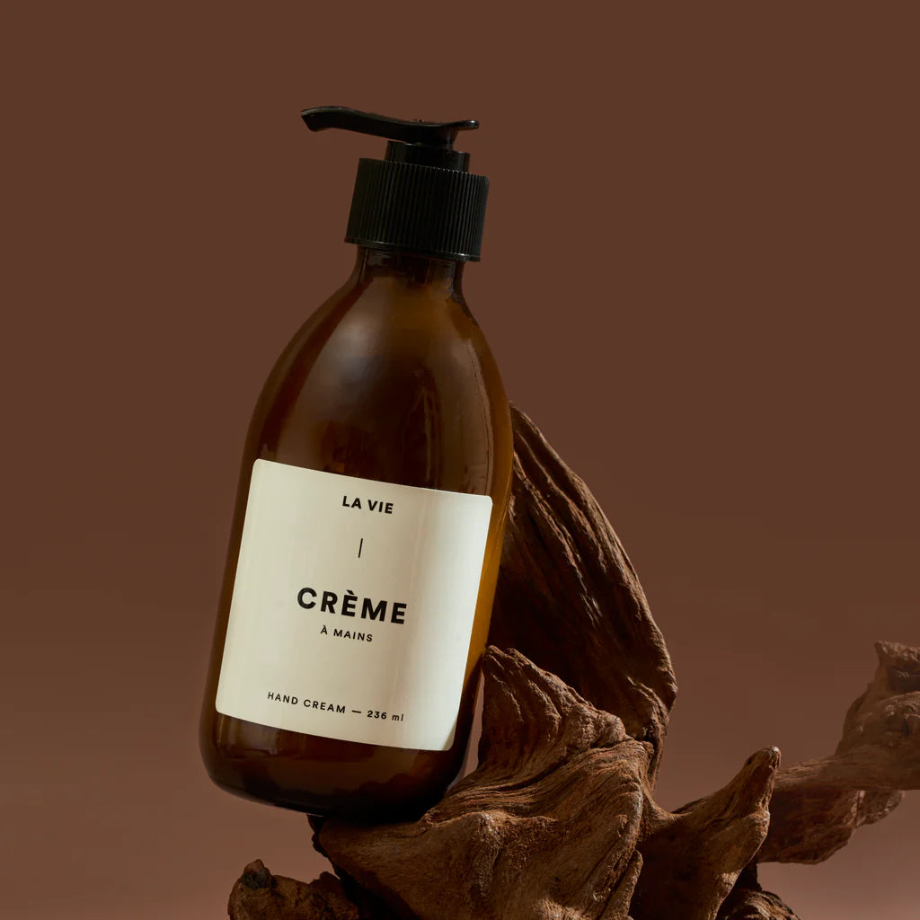 Brown bottle of 'La Vie Crème   Mains' hand cream with a label on a brown background