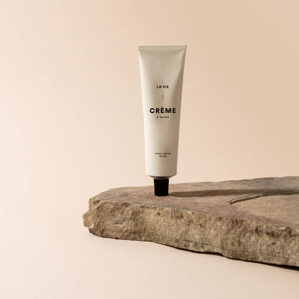 Tube of 'La Vie en Crème' hand cream on a stone surface with a beige background