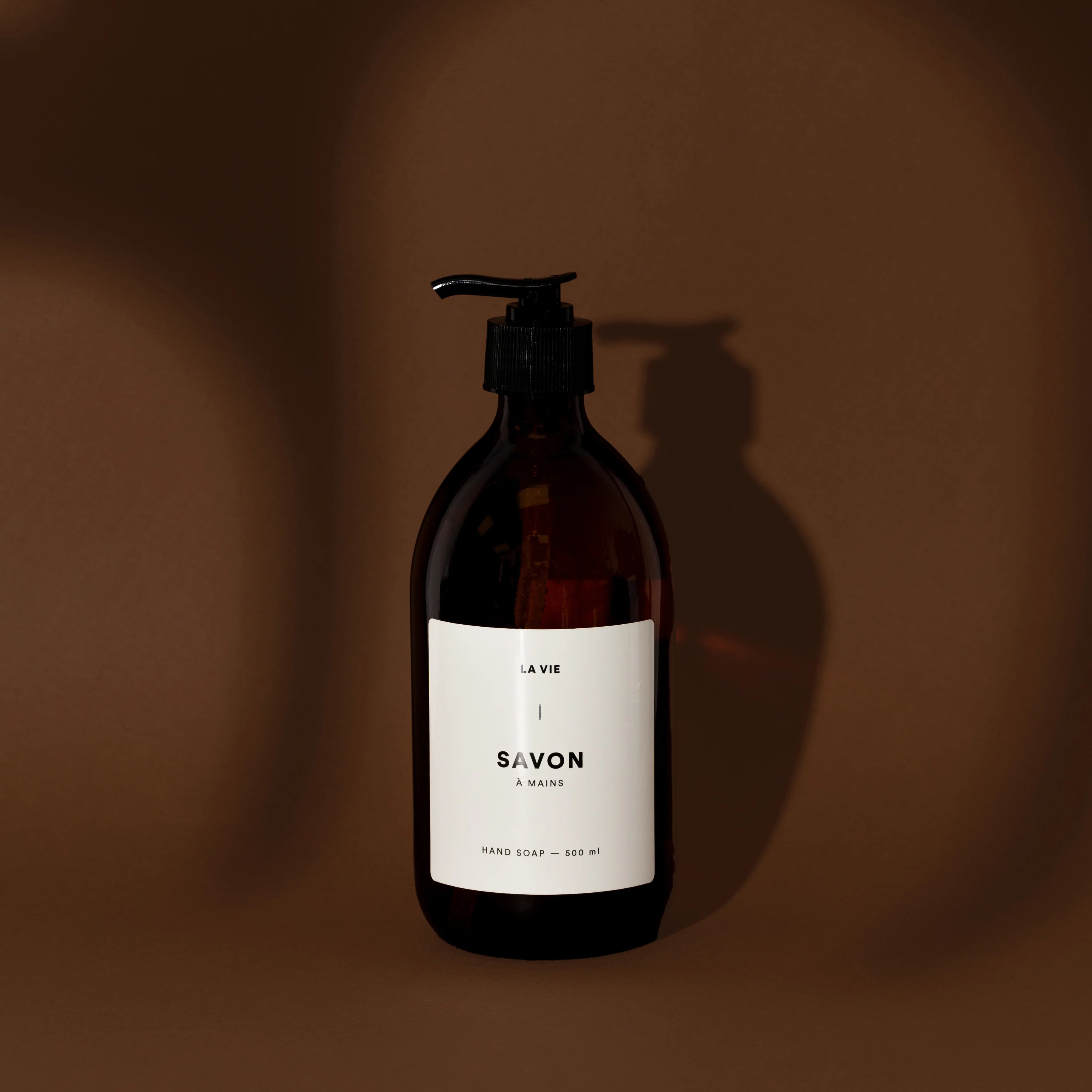 Brown soap bottle with pump and white label on a brown background