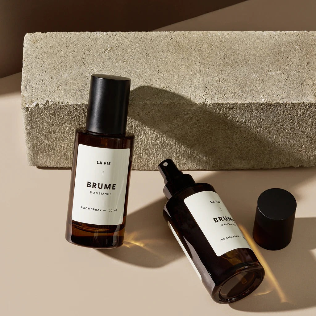 Two bottles of 'BRUME' with labels on a neutral background