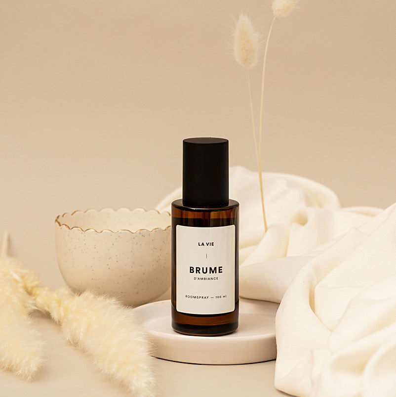 Bottle of 'Brume' by La Vie on a beige background with decorative elements