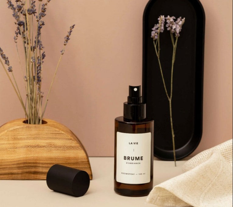 Bottle of 'La Vie Brume' on a neutral background with decorative elements.