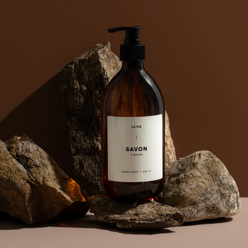 Brown soap bottle with a label on rocks against a brown background
