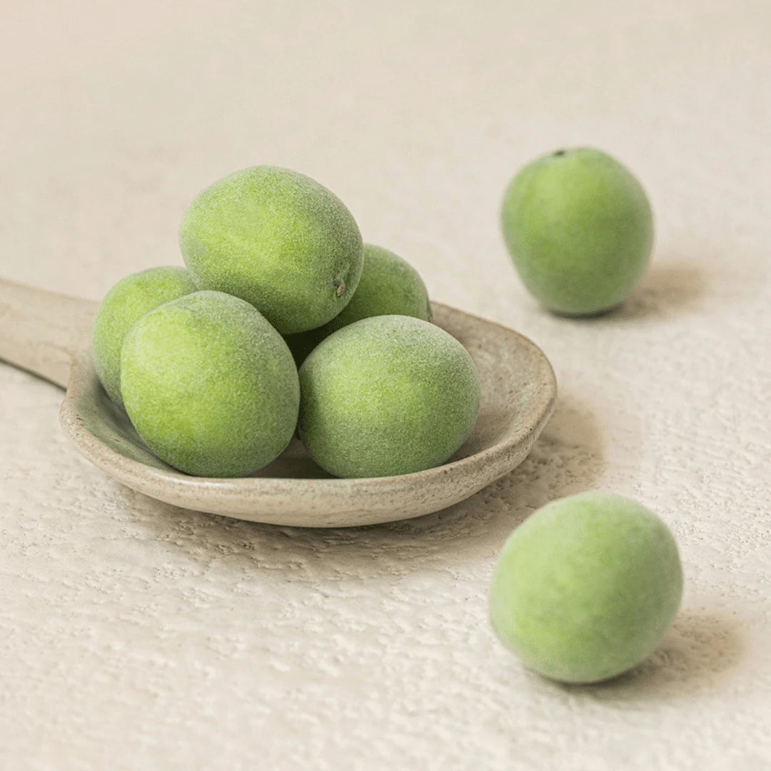 Green fruits on a stone plate with a plain background