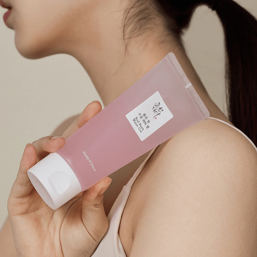 Person holding a pink skincare product with a white cap