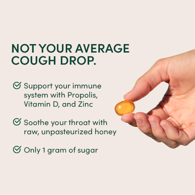 Hand holding a cough drop with product features listed on a beige background