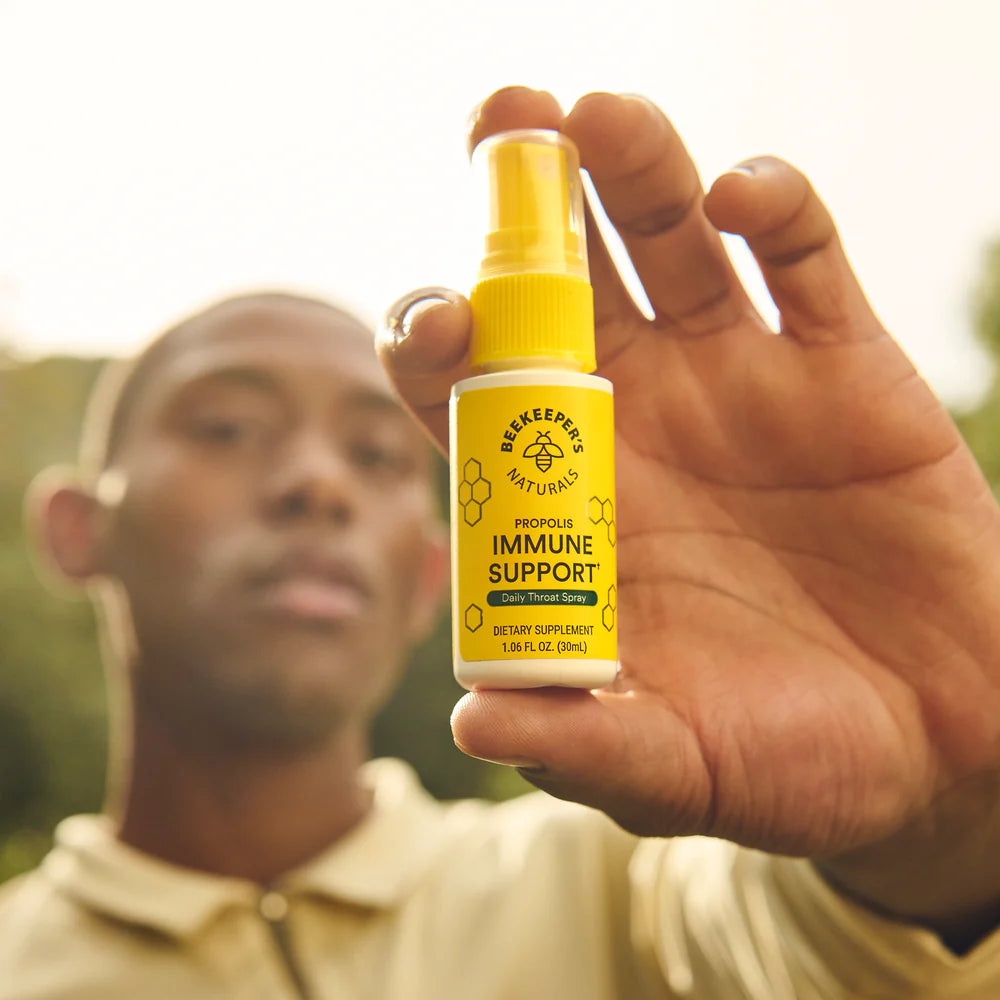 Hand holding a yellow supplement bottle labeled 'Immune Support' with a blurred background