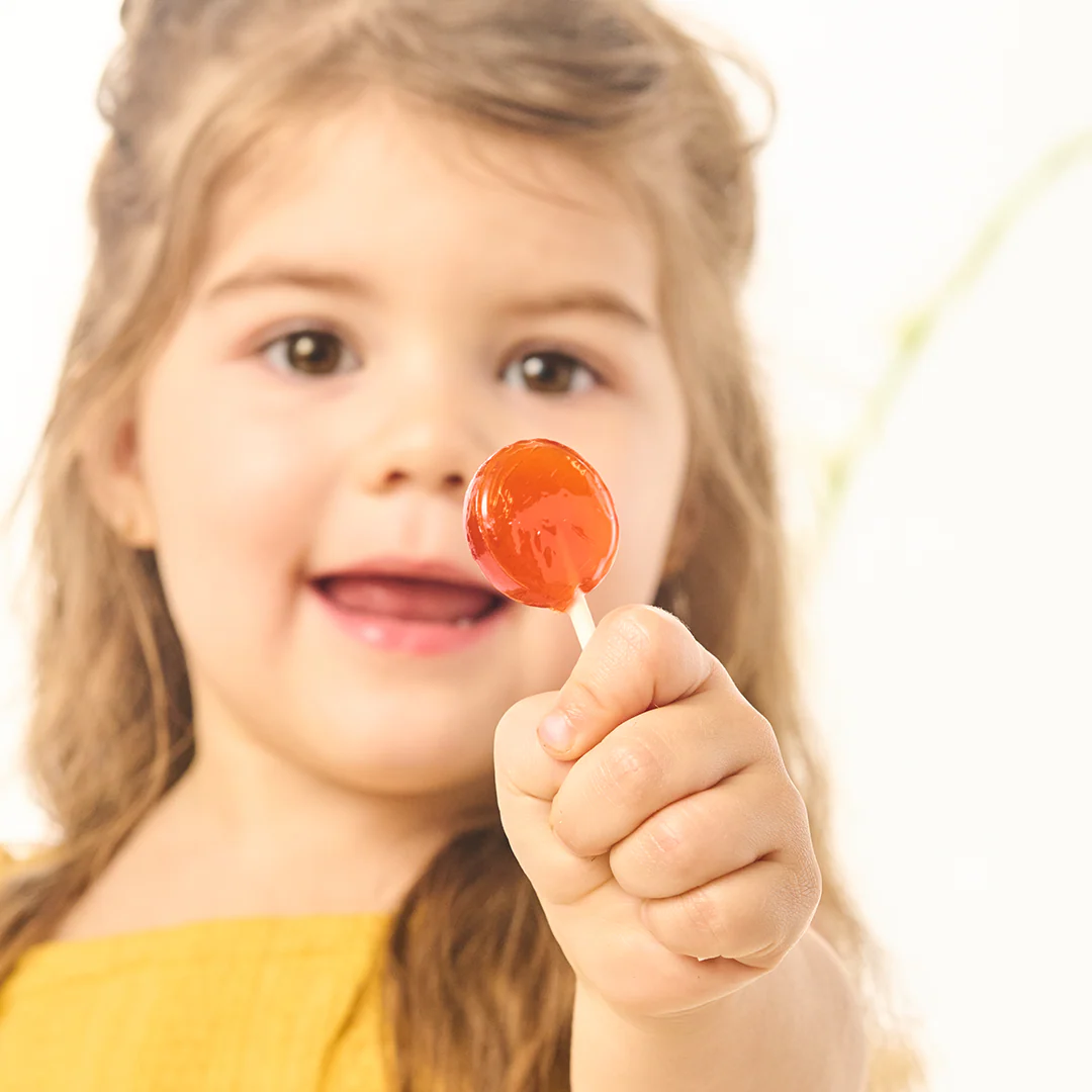 Young girl holding a red lollipop against a white background