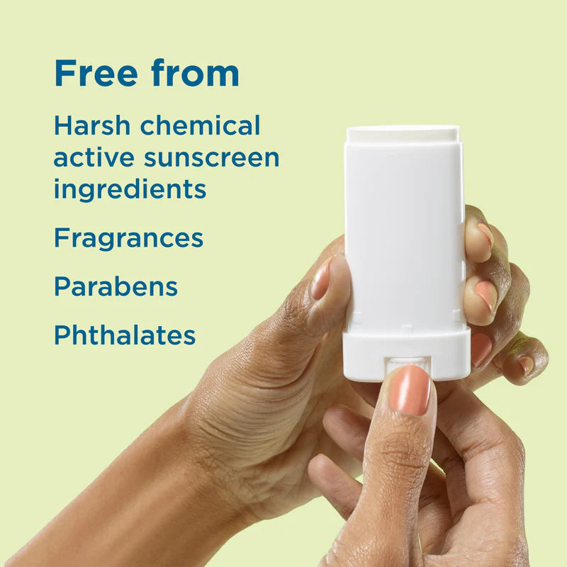 Hand holding a white stick with text about chemical-free sunscreen ingredients on a light green background