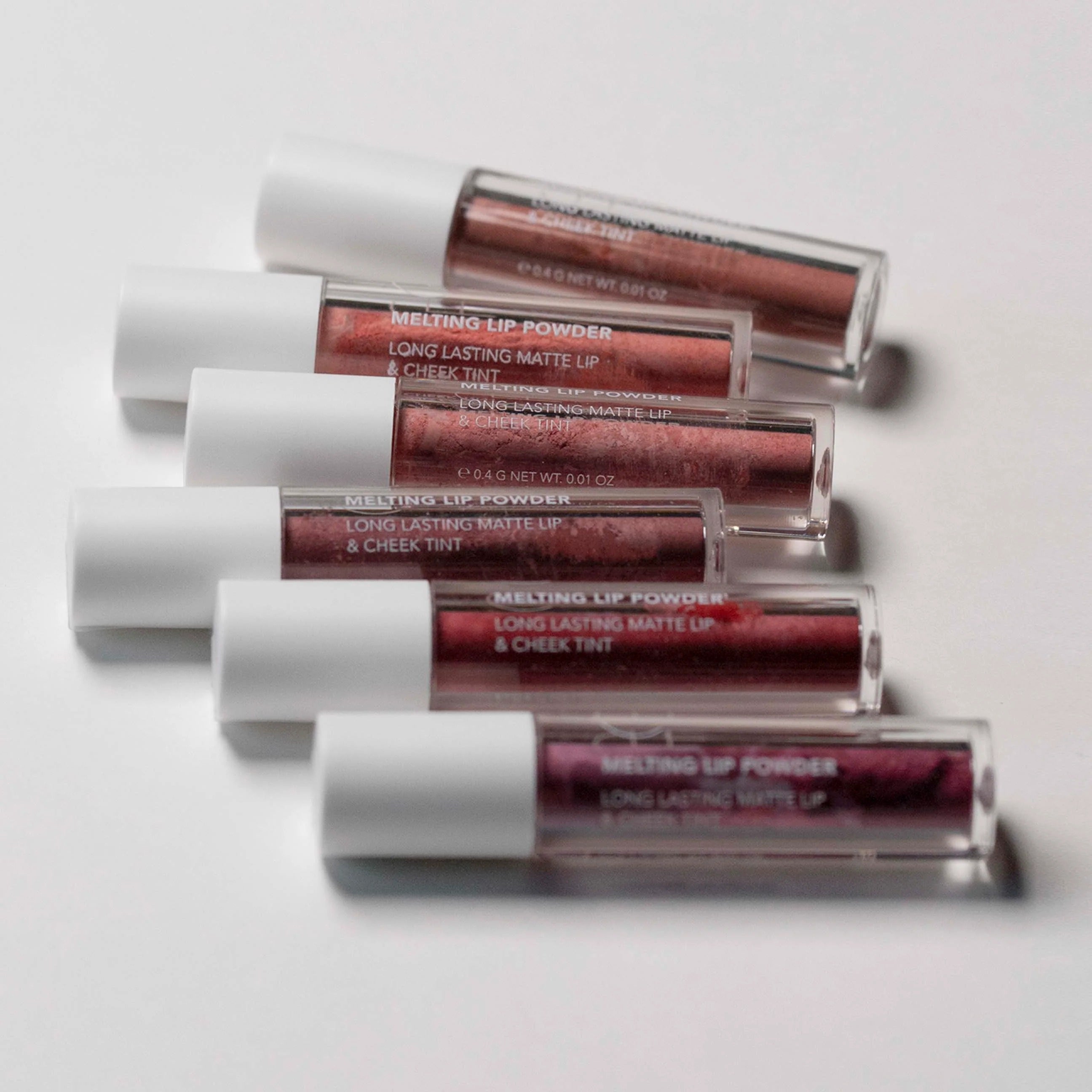 Set of lip powder products with red and brown shades on a white background