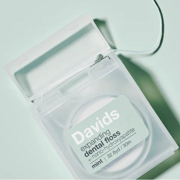 Davids dental floss container on a light green background