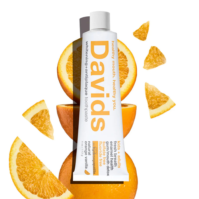 Davids toothpaste tube surrounded by orange slices on a white background