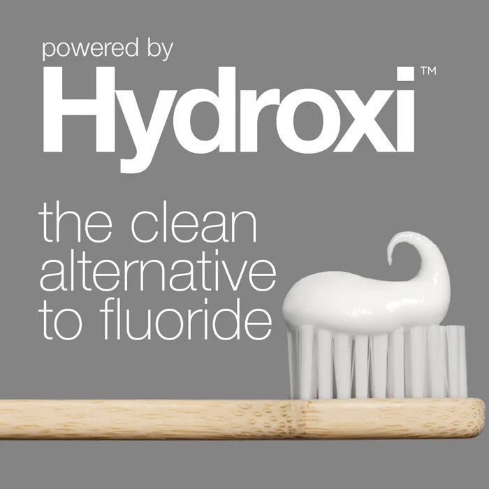 White toothbrush with wooden handle on gray background, featuring Hydroxi branding.