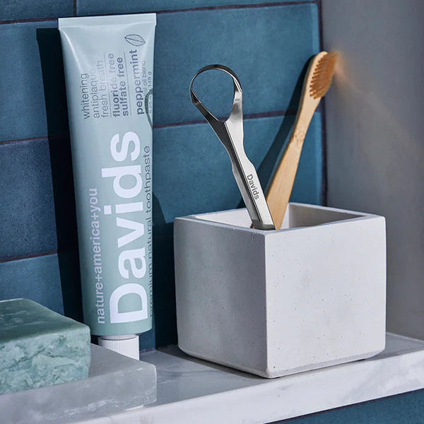 Bathroom shelf with Davids toothpaste, soap, and dental tools against a blue tiled wall.