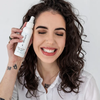 Woman holding a white spray bottle with 'e11ement' branding against a plain background