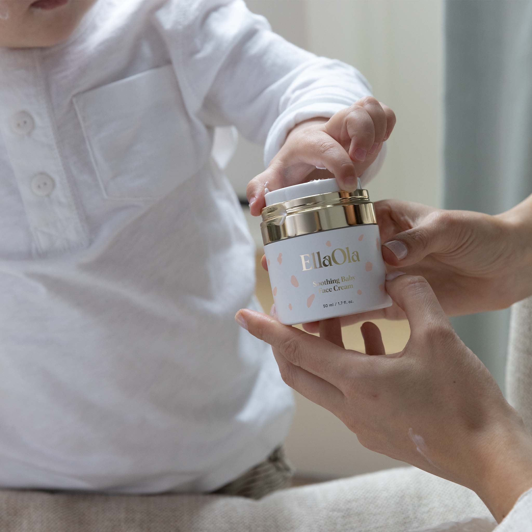 Person holding a jar of EllaOla cream for a child to touch