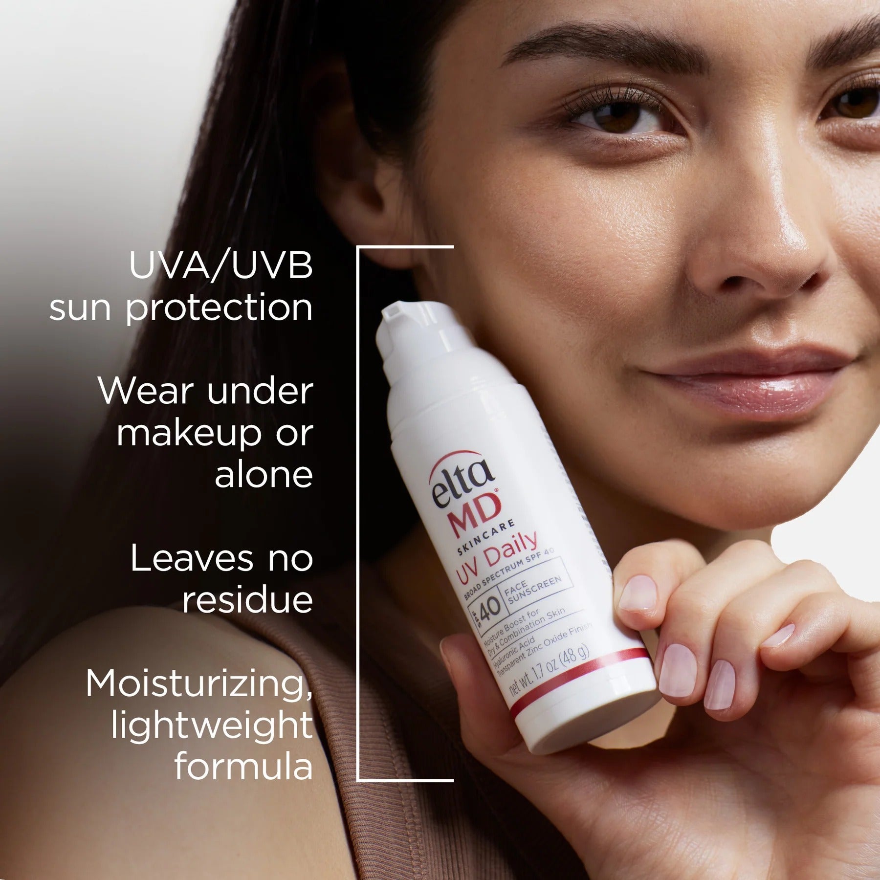 Woman holding a bottle of Elta MD sunscreen with product features listed.