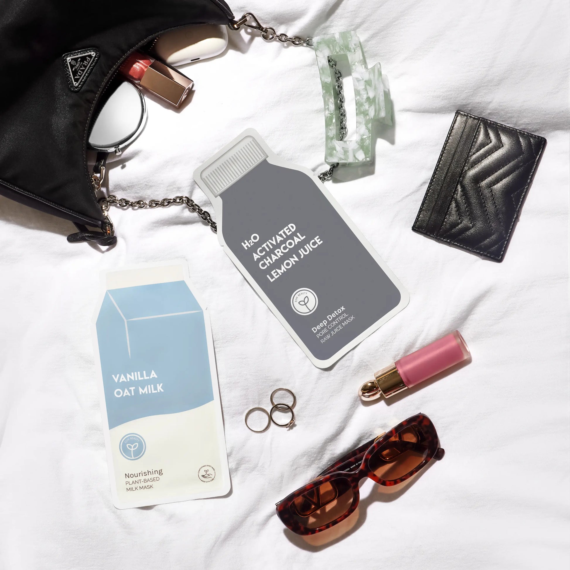 Collection of beauty and lifestyle products including a bottle, box, sunglasses, and lip gloss on a white surface.