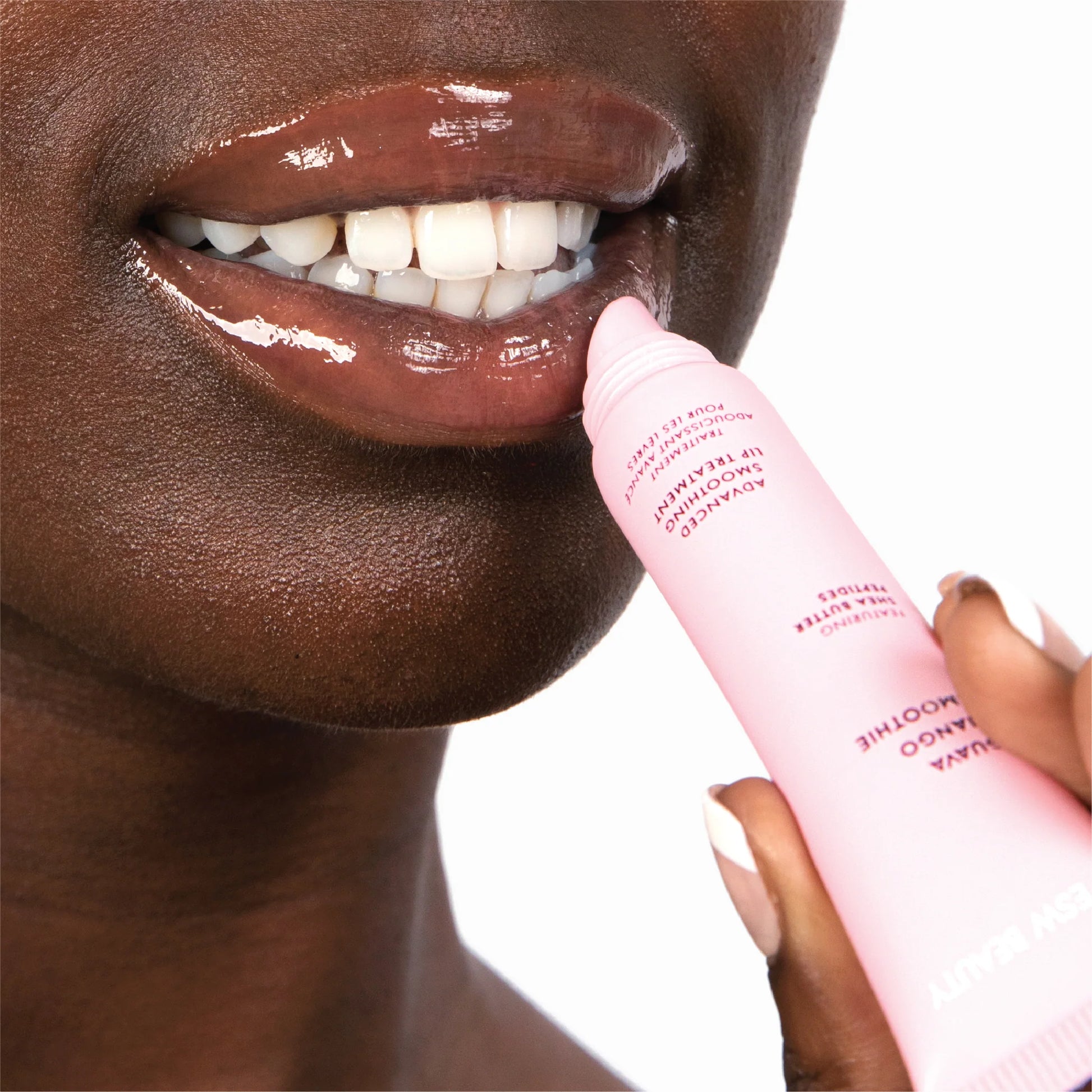 Close-up of a person applying pink lip balm to their lips with a white background