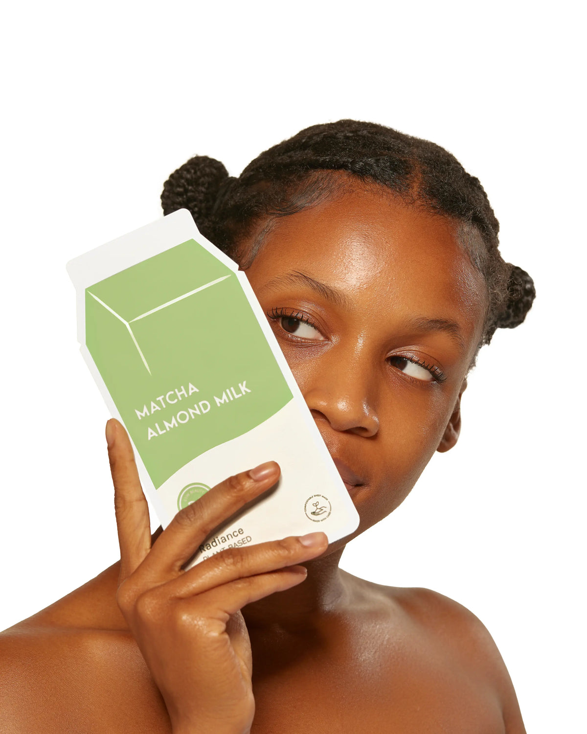 Woman holding a matcha almond milk package against a white background
