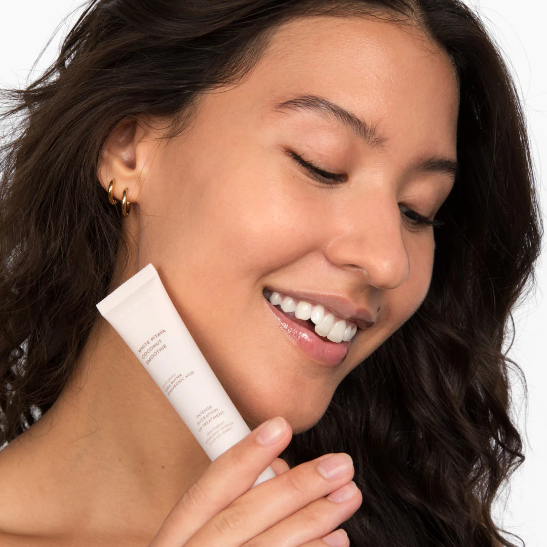 Model holding ESW Beauty White Pitaya Coconut Lip Treatment, demonstrating glossy, hydrated lips using a clean beauty formula from The Pharmacy Lab