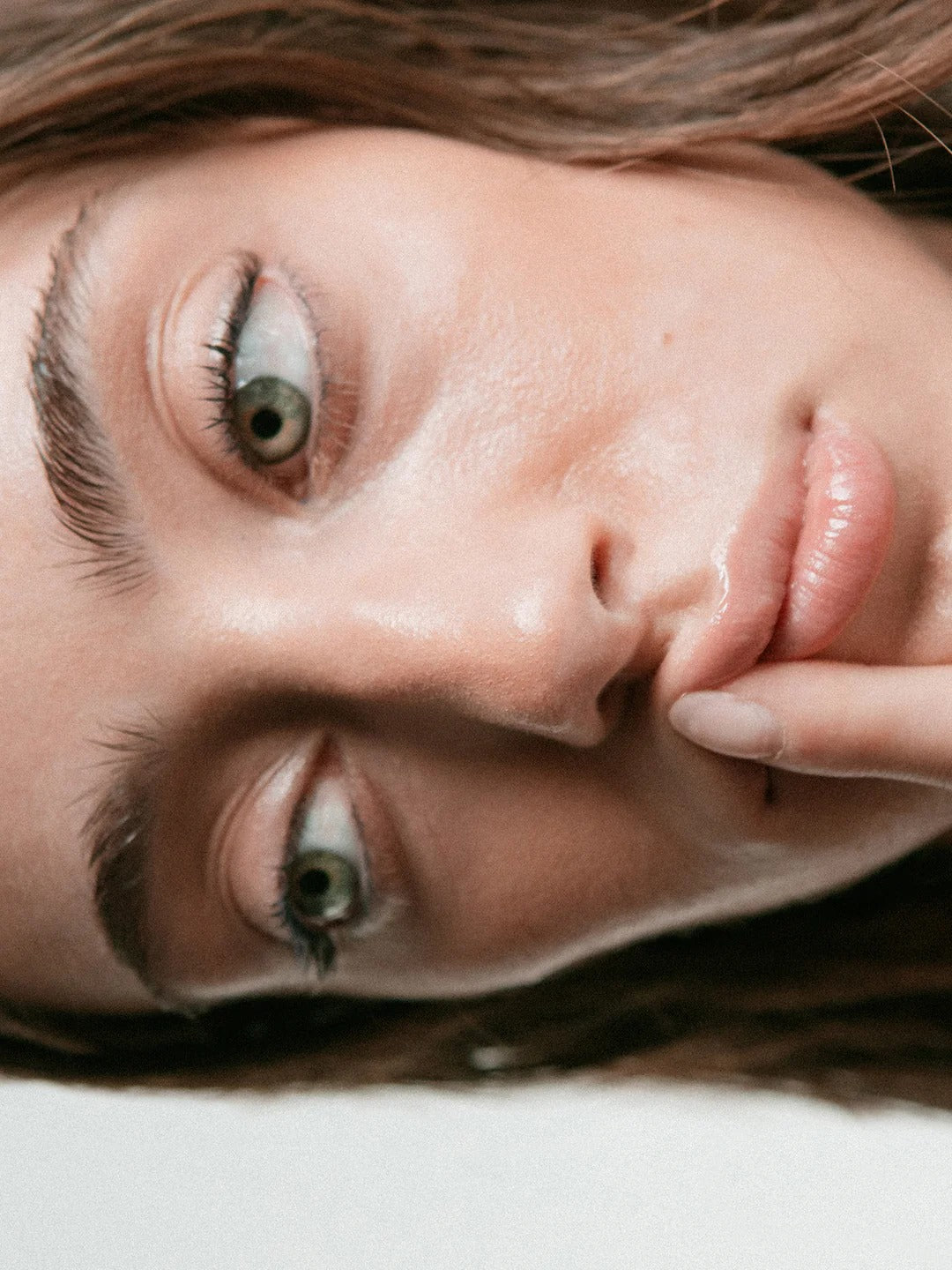 Close-up of a woman's face with a neutral expression on a light background