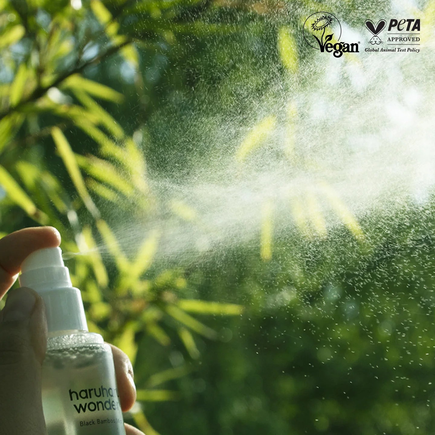 Hand holding a spray bottle with greenery in the background, featuring PETA and Vegan logos.