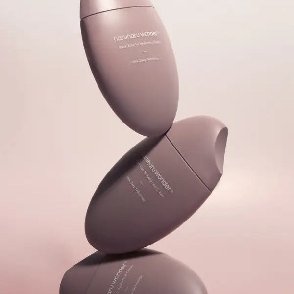 Two pink skincare bottles stacked on a light pink background