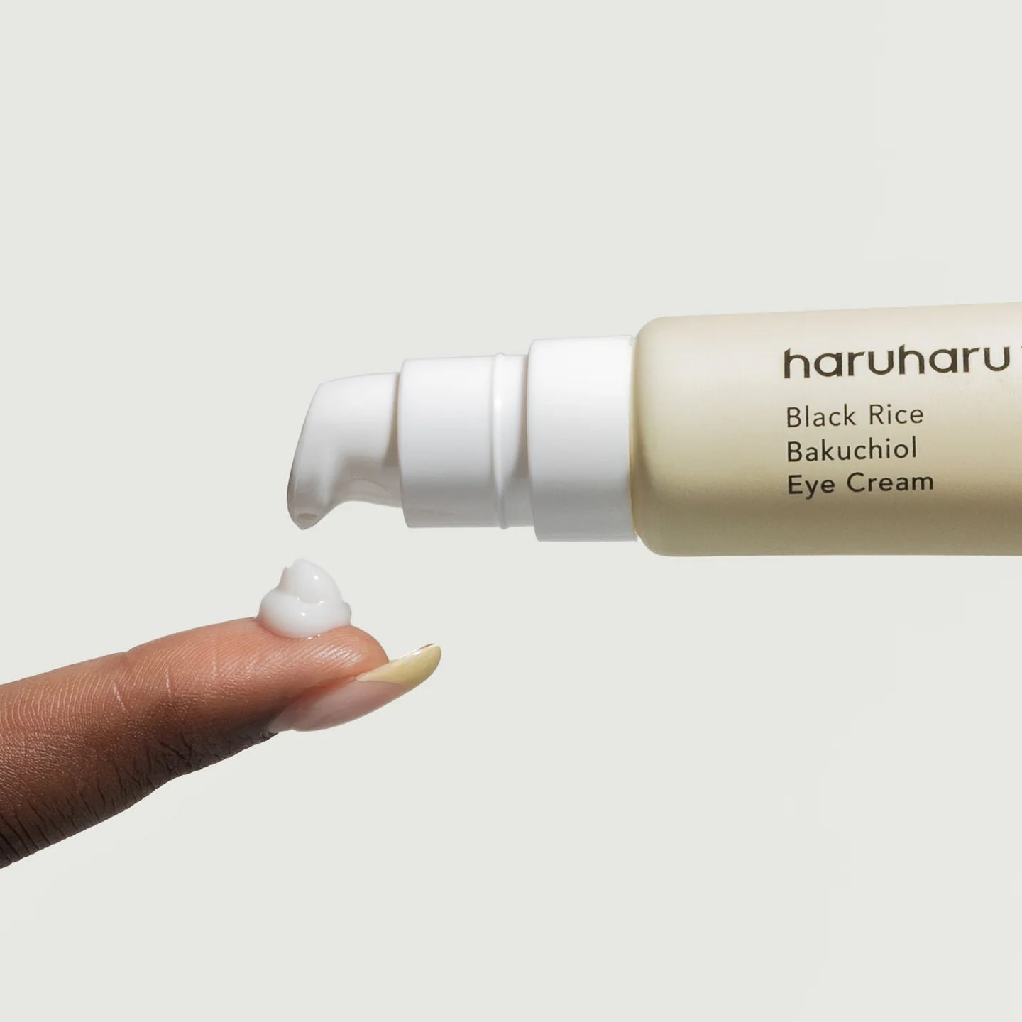 Haruharu Black Rice Bakuchiol Eye Cream with a hand applying cream on a light background