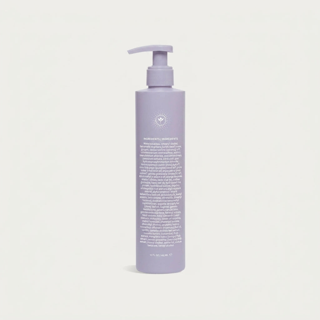 A lavender pump bottle of hair product on a clean, light off-white background. The bottle features a matching lavender pump dispenser and contains white text detailing the ingredients and instructions.